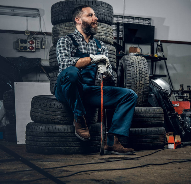 Механік сидить на старих шинах
 - Фото, зображення