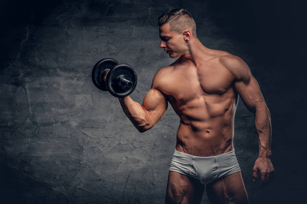 Shirtless muscular man holds dumbbell - 写真・画像