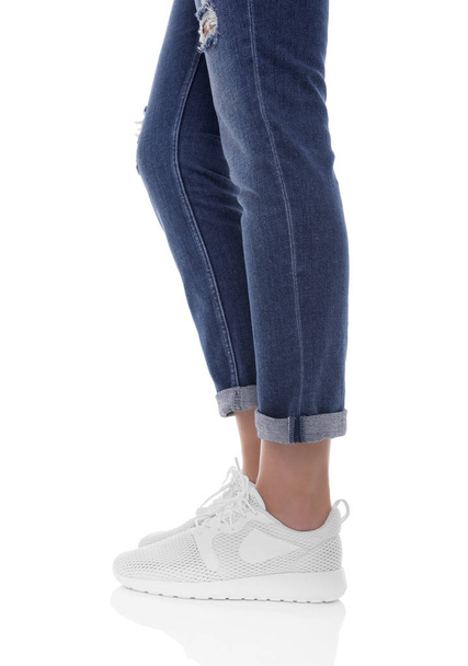 Womens legs in jeans and sneakers. - Фото, изображение