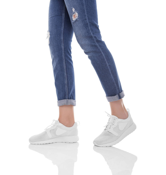 Womens legs in jeans and sneakers. - Photo, image