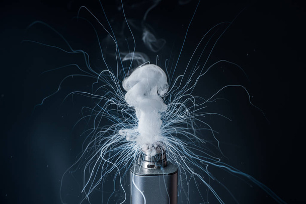Electronic Cigarette on a black background and smoke from it - Foto, Imagen
