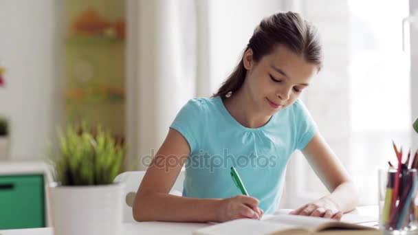 happy girl with book writing to notebook at home - Imágenes, Vídeo