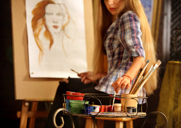 アーティストのスタジオのイーゼルの絵画します。女の子ペイント ブラシと女性のポートレート. - 写真・画像