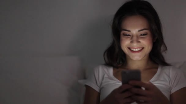 happy young woman with smartphone in bed at night - Footage, Video