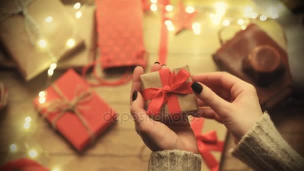 Female hands wrapping gift on wooden background - Footage, Video