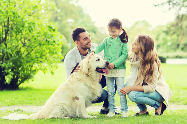 happy family with labrador retriever dog in park - Фото, изображение