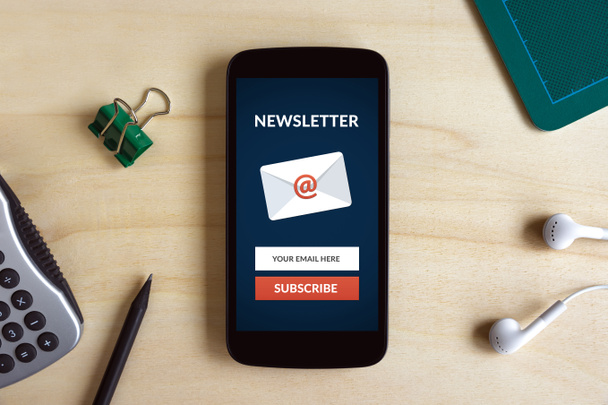 Subscribe newsletter concept on smart phone screen on wooden desk - Photo, Image