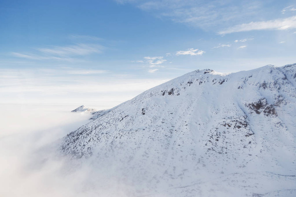 Nubes bajas envuelven el pico nevado de la montaña en los Tatras
. - Foto, imagen