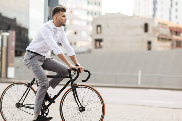 man with headphones riding bicycle on city street - Fotografie, Obrázek