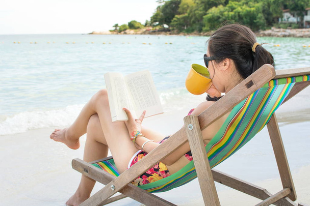 Κορίτσι διαβάζοντας ένα βιβλίο στην ξαπλώστρα δίπλα στη θάλασσα - Φωτογραφία, εικόνα