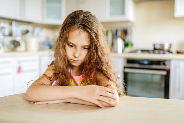 Little beautiful sad girl sits at table - Photo, image