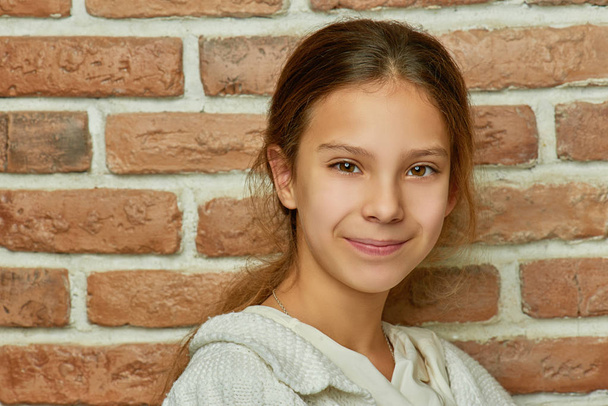 Pequeña hermosa chica sonriente cerca de la pared de ladrillo
 - Foto, Imagen
