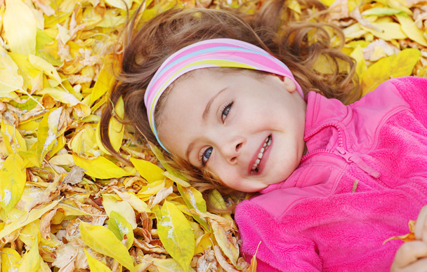Child lying on leaves - Φωτογραφία, εικόνα