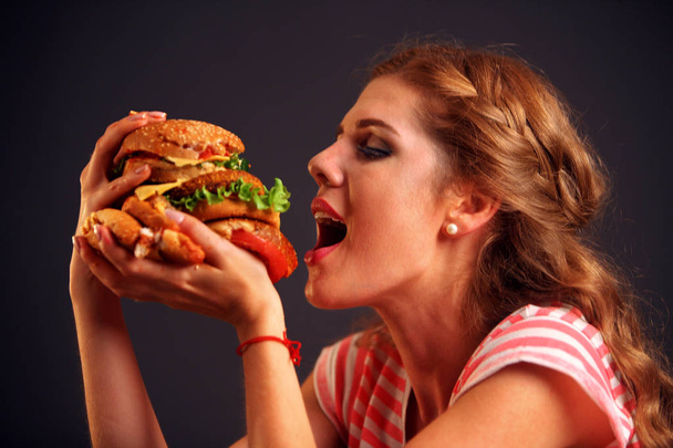 Menina abriu a boca, segurando um hambúrguer em suas mãos estendidas e fechou os olhos
. - Foto, Imagem
