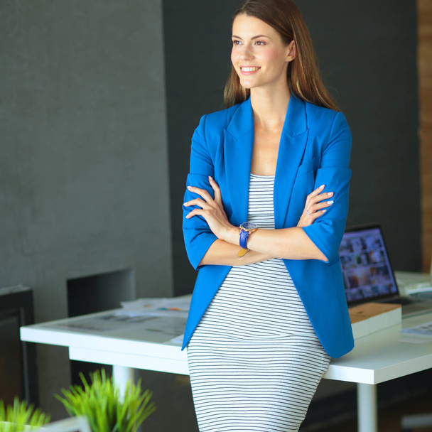 Portrait of a beautiful business woman standing near her workplace - Foto, Bild