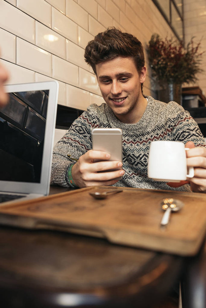 Дружній чоловік використовує свій мобільний телефон у кав'ярні
. - Фото, зображення