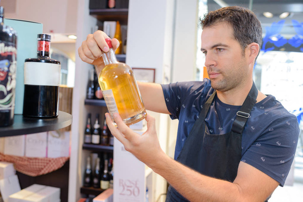 Shop assistant holding bottle of alcohol - Photo, Image