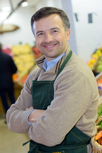 portrait of a handsome seller with arms crossed in supermarket - Foto, afbeelding
