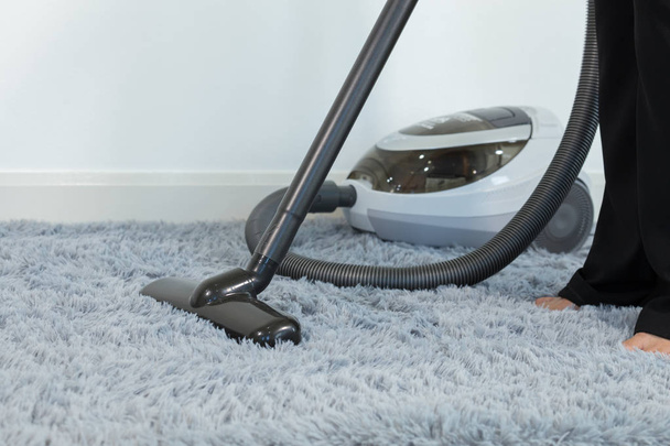 Woman cleaning carpet floor with vacuum cleaner - Fotó, kép