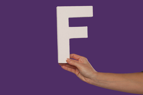 Female hand holding up the letter F from the right - Foto, afbeelding