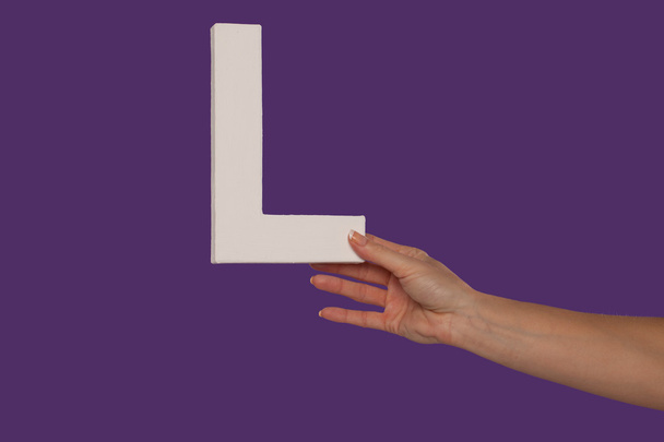 Female hand holding up the letter L from the right - Photo, Image