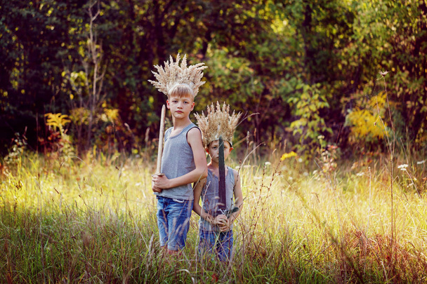Portrait Two Brothers have a crown from dry grass on the head and swords in hands. Joy and play concept - Foto, immagini