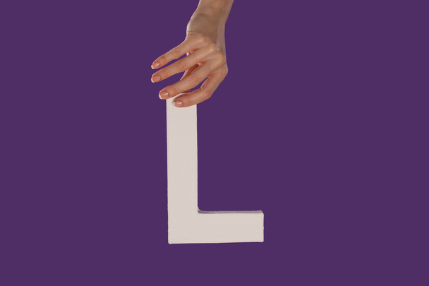 Женщина держит в руках букву L сверху.
 - Фото, изображение