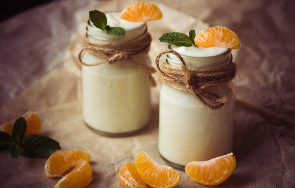 Organic yougurt with fresh tangerine and mint in glass jars  - Photo, Image