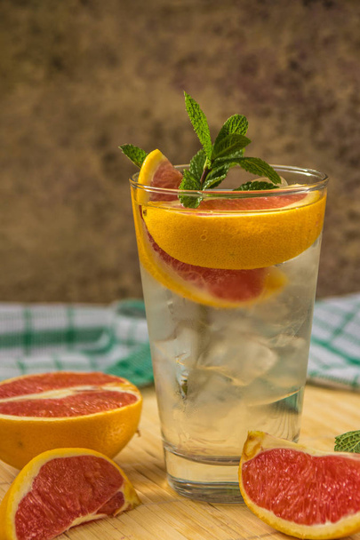 Water with ice, green mint and red orange in a glass - Fotografie, Obrázek