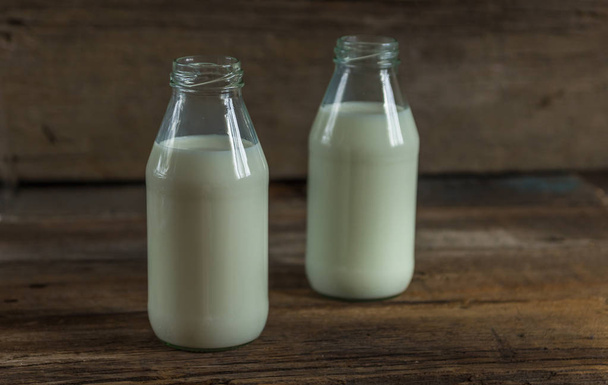 melk in een fles op een houten achtergrond - Foto, afbeelding