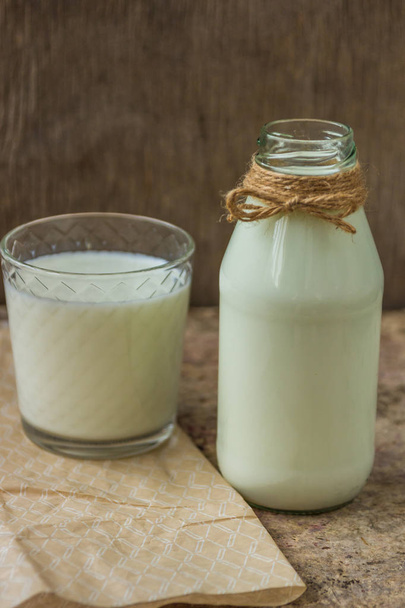milk in a bottle on a wooden background - Foto, afbeelding
