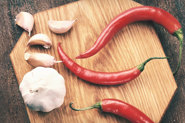 Garlic and hot peppers on the wooden board - Foto, Imagen