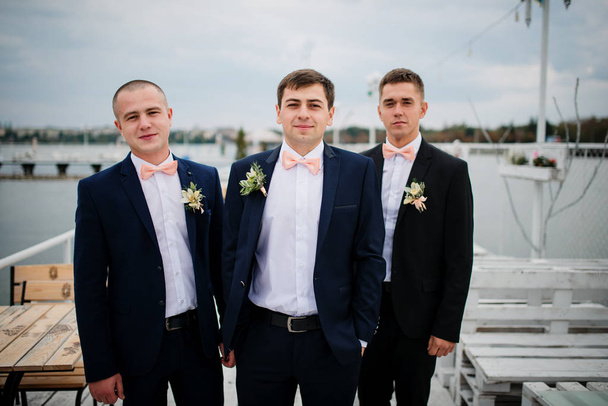 Groom with best mans posed on the pier berth at cloudy wedding d - Photo, image