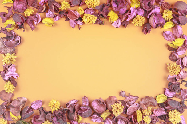 De samenstelling van de droge bloemen op kleurrijke achtergrond. Frame gemaakt van gedroogde bloemen en bladeren. Bovenaanzicht, plat lag. - Foto, afbeelding
