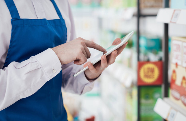 Supermarket clerk using digital tablet - 写真・画像
