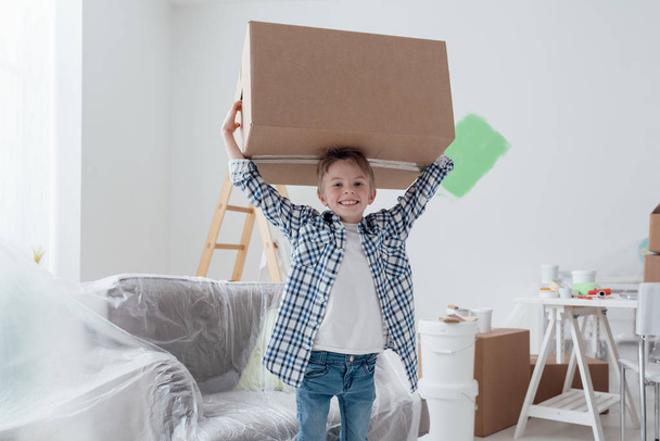 Smiling boy carrying huge box - Foto, afbeelding