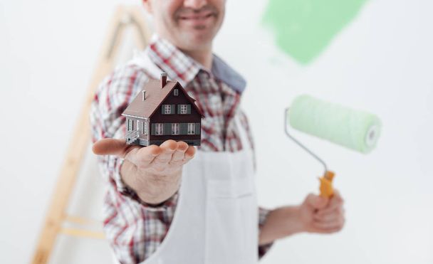Painter holding model of house - Foto, imagen