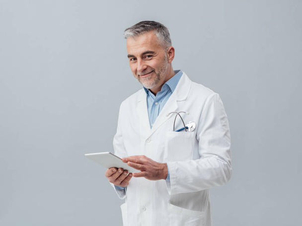 Confident mature doctor with tablet - 写真・画像