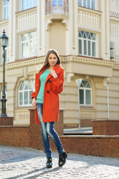 Beautiful young woman in coat walking down the street - Fotó, kép