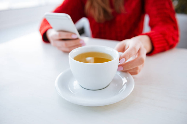 Cropped image of lady sitting in cafe holding tea. - 写真・画像