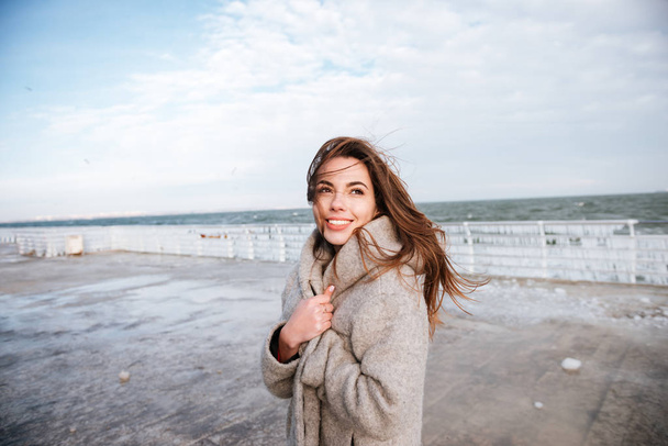 Happy woman standing and smiling on pier in winter - Foto, afbeelding