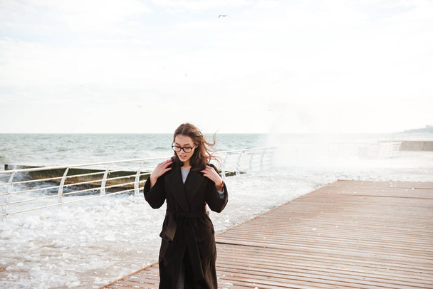 Smiling attractive young woman walking on pier in winter - Foto, immagini