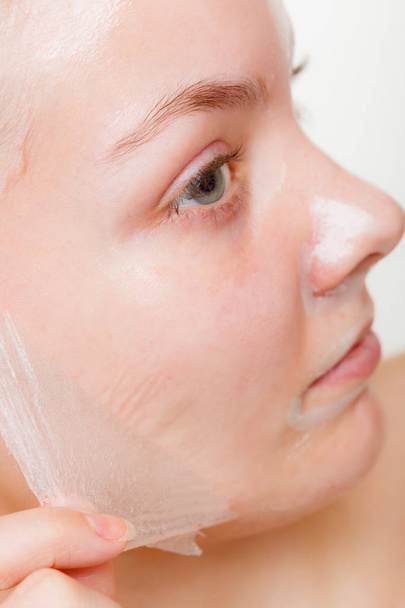 Woman removing facial peel off mask closeup - Foto, Imagen