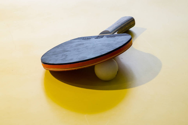 os bastões de tênis de mesa e as bolas isoladas em fundo amarelo, p
 - Foto, Imagem