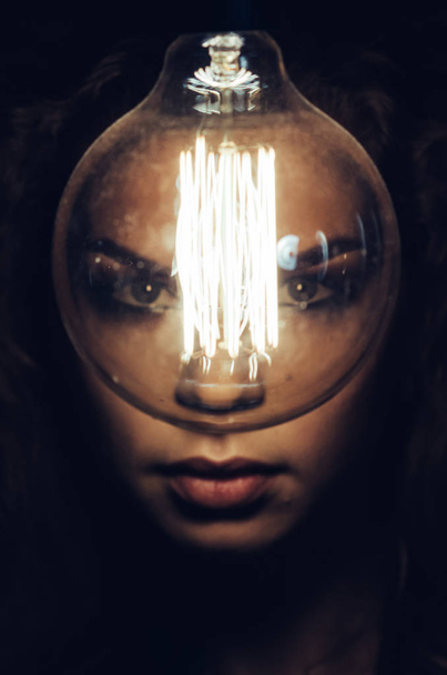 Mysterious photo of woman with light bulb. Portrait in the dark. Dangerous girl. - Foto, imagen
