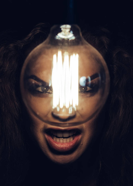 Woman in the darkness screaming on the lamp. Emotional photo. - 写真・画像