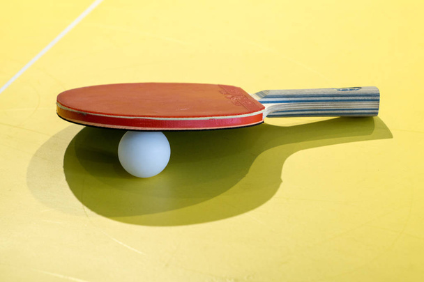 the table tennis bats and balls isolated on yellow background, p - Foto, Imagen