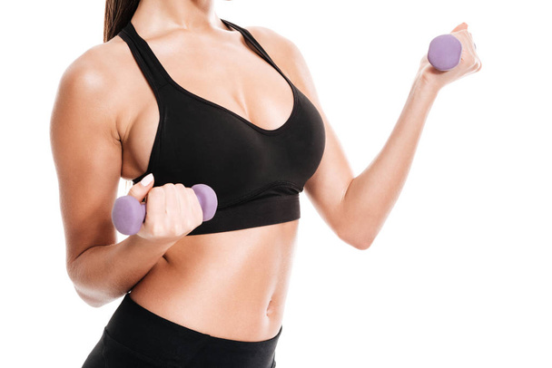 Cropped image of a beautiful fit female body holding barbells - Foto, Bild