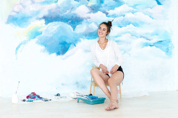 Una joven artista. Ella pintando un cielo en la pared
. - Foto, Imagen