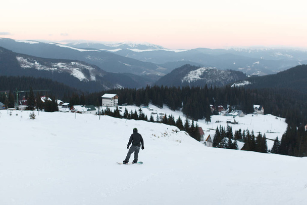 guy on a snowboard down the mountain in a snow-covered winter su - Foto, Imagen